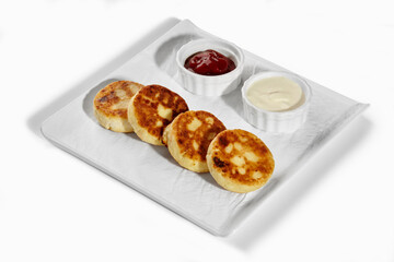 Syrniki with jam and sour cream served on white plate