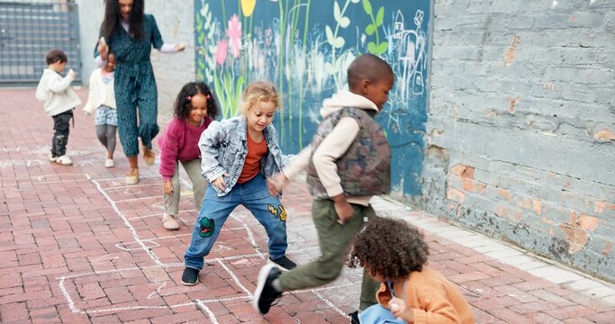 Hopscotch, kids and playing with outdoor game at Kindergarten for childhood development. Group, children or learners jumping with teacher for fun activity, hopping or skipping on school playground
