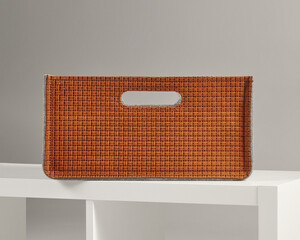 Woven orange leather basket sitting on white shelf