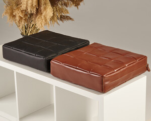 Brown and black leather pouf cushions resting on modern white shelf