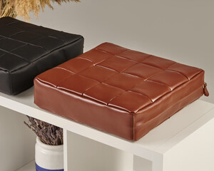 Brown and black leather cushions resting on modern white shelf