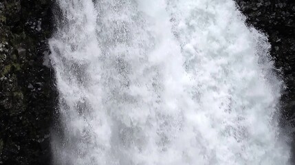 Powerful cascading waterfall from a dark rocky cliff face.