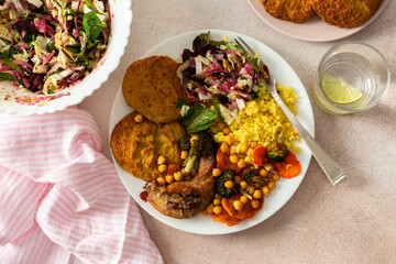 A wholesome breakfast with lentil-zucchini pancakes, millet, roasted chicken neck, sweet potatoes, broccoli, carrots, chickpeas, and a fresh mix salad with radish, nuts, and mung bean sprouts