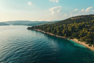 Fototapeta premium Scenic view of the green coastline with mountains meeting the blue sea under the summer sky