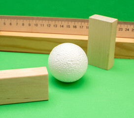 Still life with wooden blocks and a a plastic foam ball on green background	