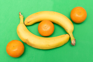 Bananas and tangerine on a green background	