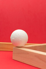 Still life with wooden blocks and a a plastic foam ball on red background	