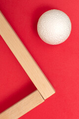Still life with wooden blocks and a a plastic foam ball on red background	