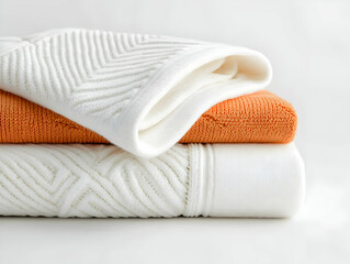 A stack of folded soft textiles. The textures offer a sense of warmth and comfort. Perfect for lifestyle and home decor content.