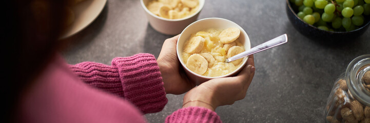 Header with woman eating breakfast in the kitchen