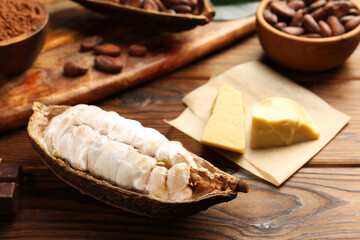 Cocoa pod with beans and butter on wooden table, closeup
