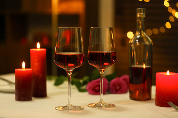 Romantic place setting with red wine and burning candles on table