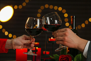 Couple clinking glasses of wine in restaurant, closeup. Romantic dinner