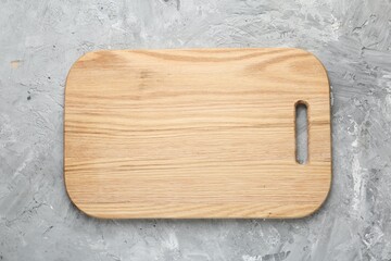 One wooden serving board on light grey textured table, top view. Space for text