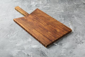 Fototapeta premium One wooden serving board on light grey textured table, closeup. Space for text