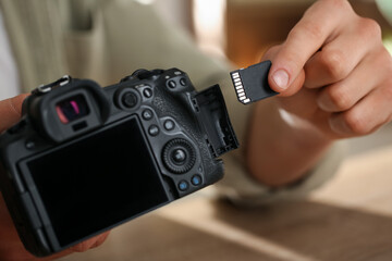Man inserting SD memory card into photo camera, closeup