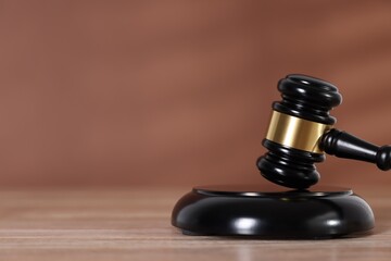 Judge's gavel and sound block on wooden table against brown background, closeup. Space for text