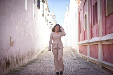Young, pretty, brown-haired woman, wearing a light gray jacket suit, with one hand in her hair,...