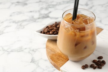 Tasty iced coffee and beans on white marble table, closeup. Space for text
