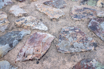 A close-up of weathered schist stones with natural lichen patterns, showcasing geological textures and rustic pavement construction, captured in Portugal