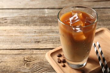 Tasty iced coffee and beans on wooden table, closeup. Space for text