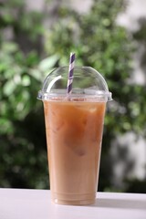 Tasty iced coffee on white table against blurred background