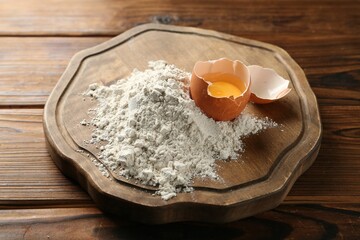Pile of flour and egg on wooden table, closeup