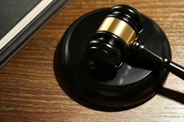 Judge's gavel, sound block and books on wooden table, closeup