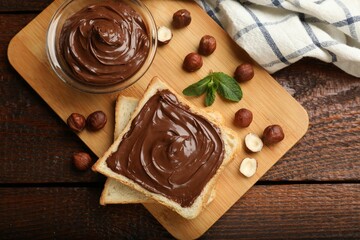 Toast with tasty chocolate hazelnut spread, nuts and mint on wooden table, flat lay