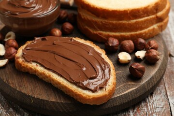Toast with chocolate hazelnut spread and nuts on wooden table, closeup