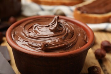 Tasty chocolate hazelnut spread and nuts on wooden table, closeup