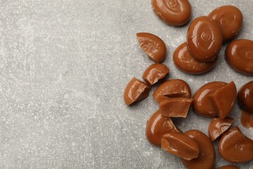 Many tasty caramel candies on grey table, flat lay. Space for text