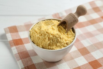 Corn flour in bowl and scoop on white table, closeup