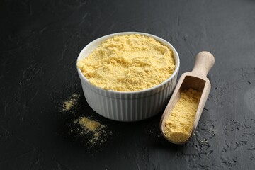 Corn flour in bowl and scoop on black textured table