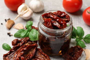 Delicious sun dried tomatoes, fresh vegetables and spices on grey table, closeup