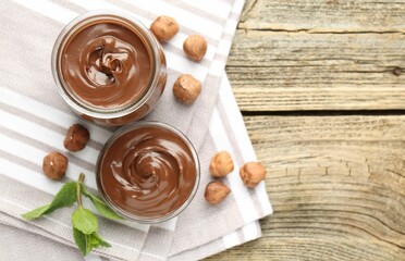 Tasty chocolate spread, hazelnuts and mint on wooden table, top view. Space for text