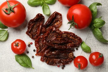 Delicious sun dried tomatoes, fresh vegetables and spices on gray textured table, flat lay
