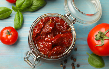 Tasty sun dried tomatoes, fresh vegetables and peppercorns on light blue wooden table, top view