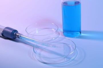 Petri dishes, micropipette and beaker with sample on light background