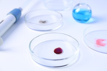 Petri dishes with samples and micropipette on white background, closeup