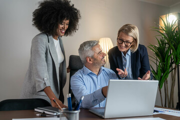 Three busy happy middle aged professional business man and two women executive leaders team using...