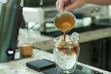 Barista carefully pouring rich espresso over ice inside cafe, capturing moment of artisan craft, expressing warmth, love, dedication of small family business, cozy inviting, Concept small business