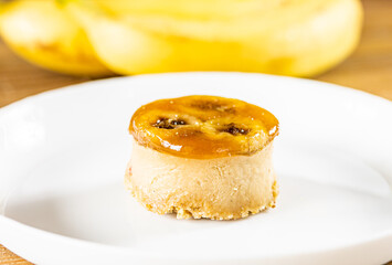 Close up of banana cake with smooth, creamy texture and sticky caramel topping on white plate. Vegan dessert.