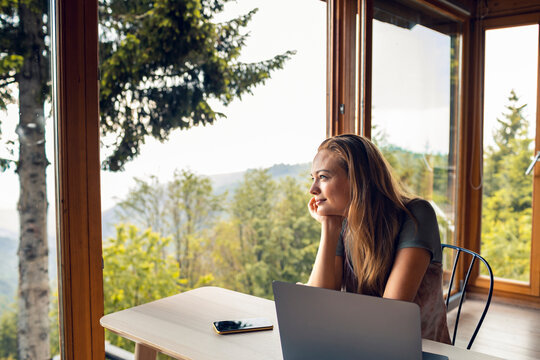 Woman working remotely in mountain cabin with scenic view
