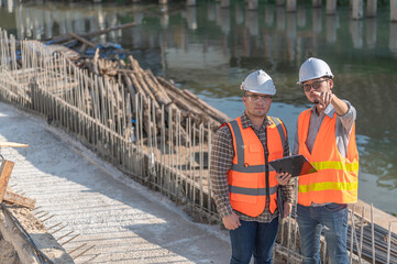 Construction engineer working on a bridge construction site over a river,Civil engineer supervising...