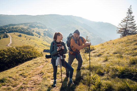 Couple hiking in mountains with trekking poles and backpacks