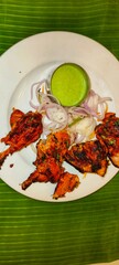 a plate of Tandoori Chicken, a popular Indian dish. The chicken pieces are marinated in a mixture of yogurt and spices, giving them a deep red or orange color, and then cooked in a tandoor 