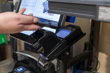 Contactless payment with smartphone at self-checkout terminal, demonstrating convenience of digital transactions in modern retail