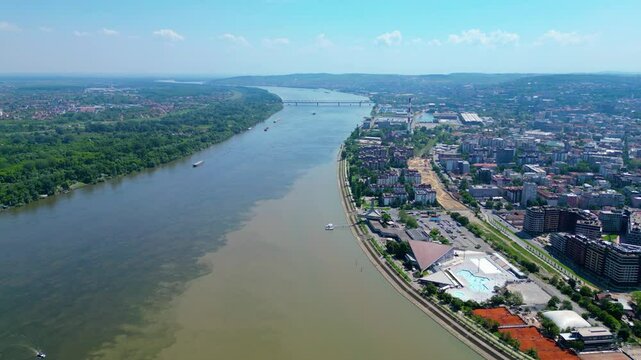Aerial view of Belgrade where the Sava and Danube rivers meet. Visible landmarks include Kalemegdan Fortress (Beogradska tvrđava), city bridges, and U&scaron;će Park &mdash; a perfect urban-meets-nature panorama