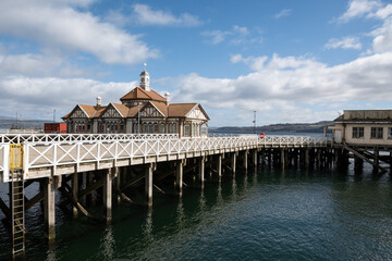 Victorian Dunoon timber ferry pier in Scotland, Category A listed wooden structure in Firth of Clyde closed to public needs renovation. Pretty historic landmark buildings on greenheart timber piles 